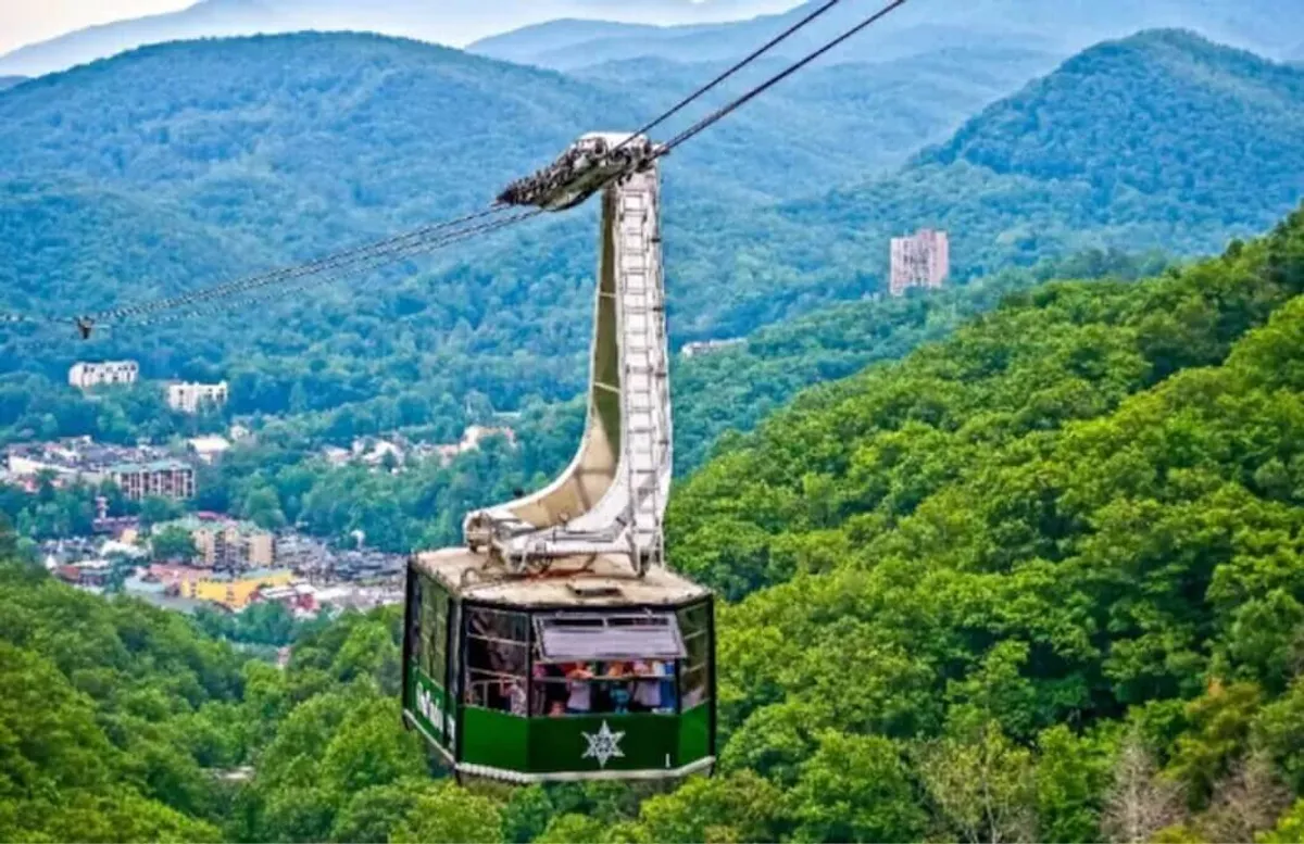 A panoramic view from a cable car reveals the vast mountain range, the charming town nestled below, and the promise of adventure in every direction. The image captures the excitement of exploration and the proximity to natural wonders.